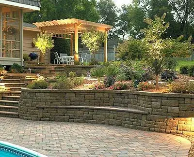 Outdoor living area with custom landscape lighting and retaining wall in Ankeny, IA.