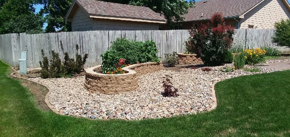 New rock mulch around a newly built hardscape feature with plantings.