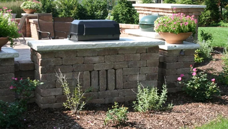 Patio, seating wall, built-in grill, and new landscaping at a home in Pleasant Hill, Iowa.