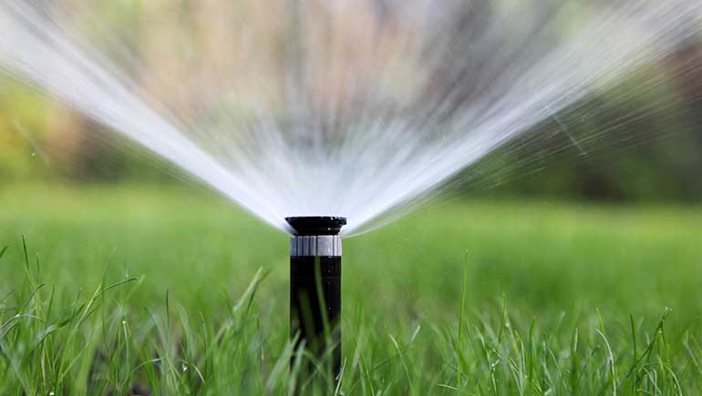 Water sprinkler irrigation watering a Des Moines, IA home lawn.
