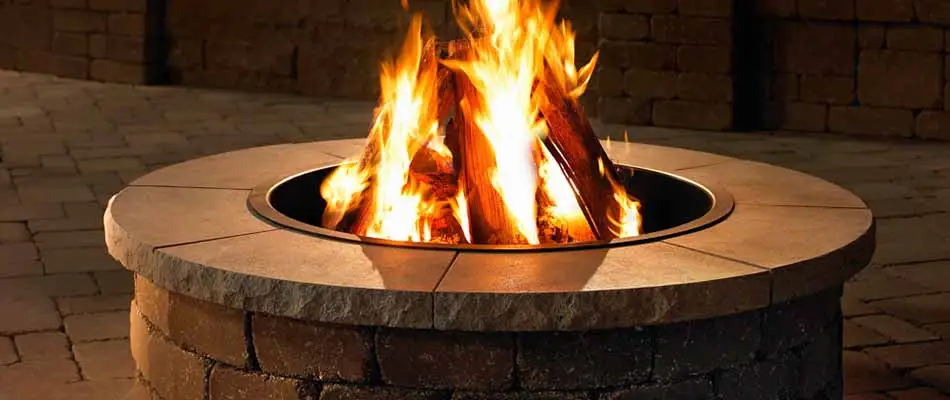 Stone fire pit with flames installed at a West Des Moines, IA home.