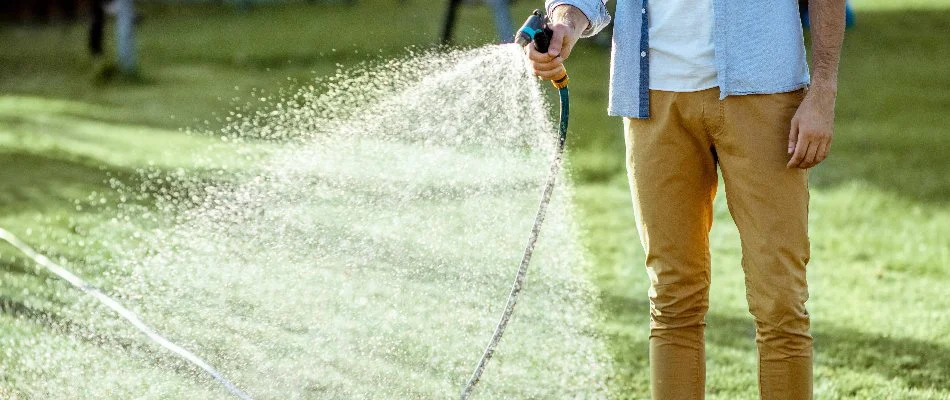 Man watering a lawn in Des Moines, IA.