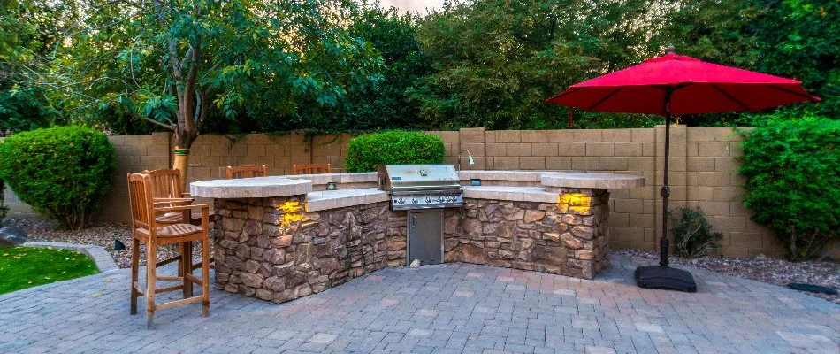 Patio in Des Moines, IA, with outdoor kitchen and a red umbrella.