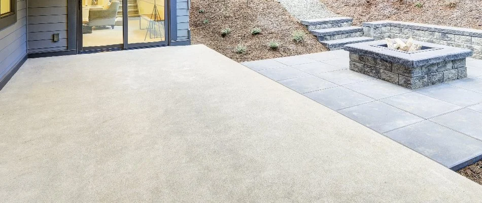 Plain concrete in a backyard in Des Moines, IA, with a fire pit.