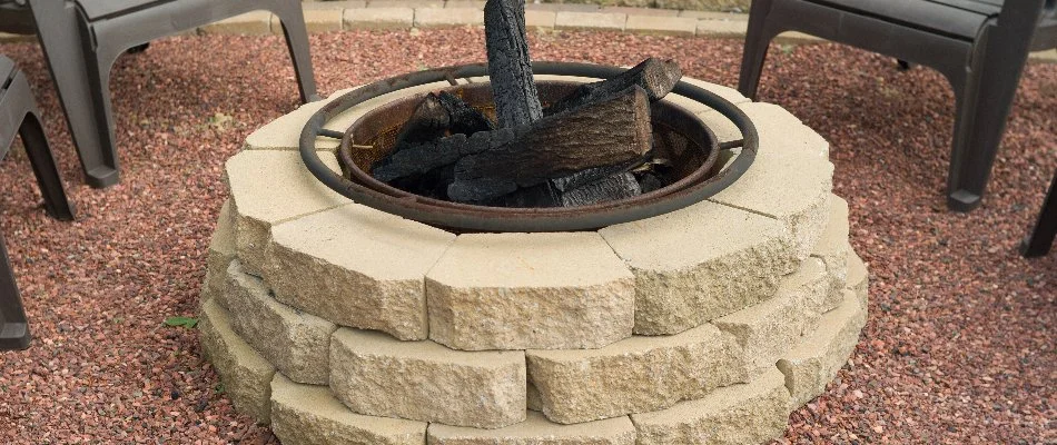 Wood-burning block fire pit in Des Moines, IA, on a gravel patio.