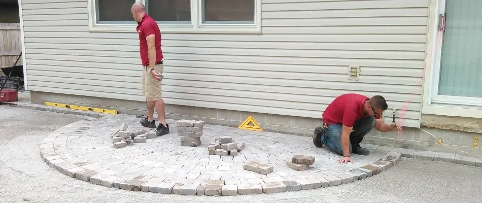 Workers installing a paver patio along a house in Des Moines, IA.