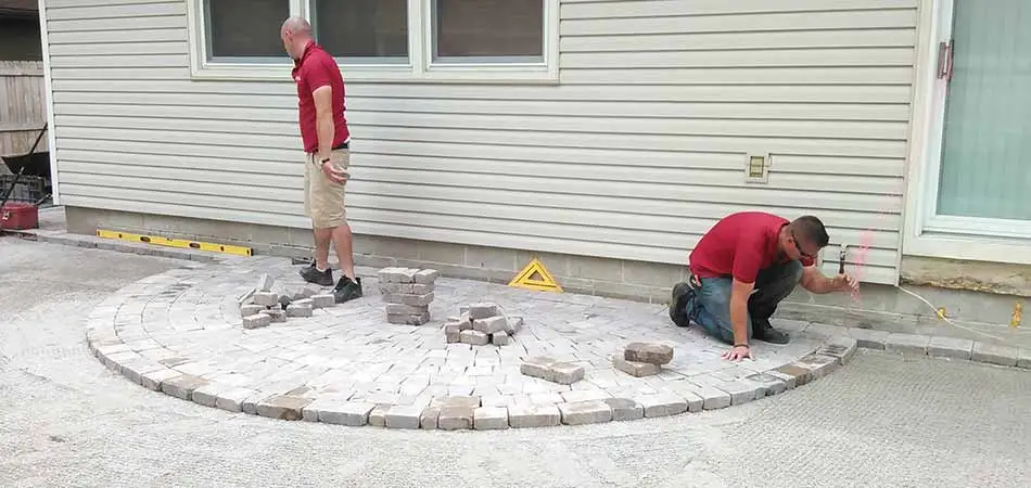 Team members from A+ Lawn & Landscape are building a paver patio for a homeowner in Des Moines.