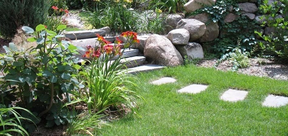 Healthy green lawn with beautiful landscaping design by our team at a home in Windsor Heights, IA.