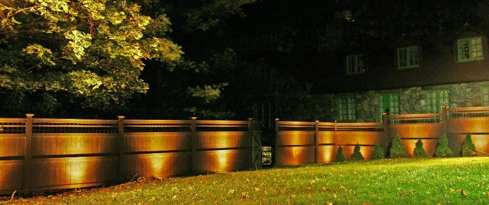 Fence and plants illuminated with lights on a property in Des Moines, IA.