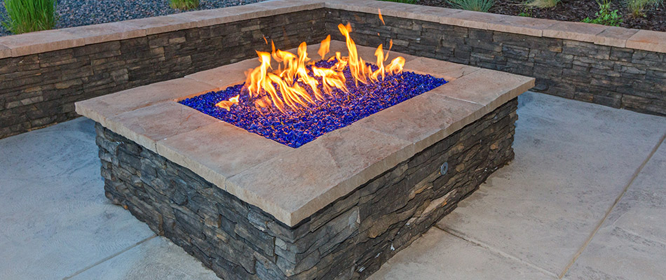 A rectangular custom gas powered fire pit installed on a patio by a home in Van Meter, IA. 