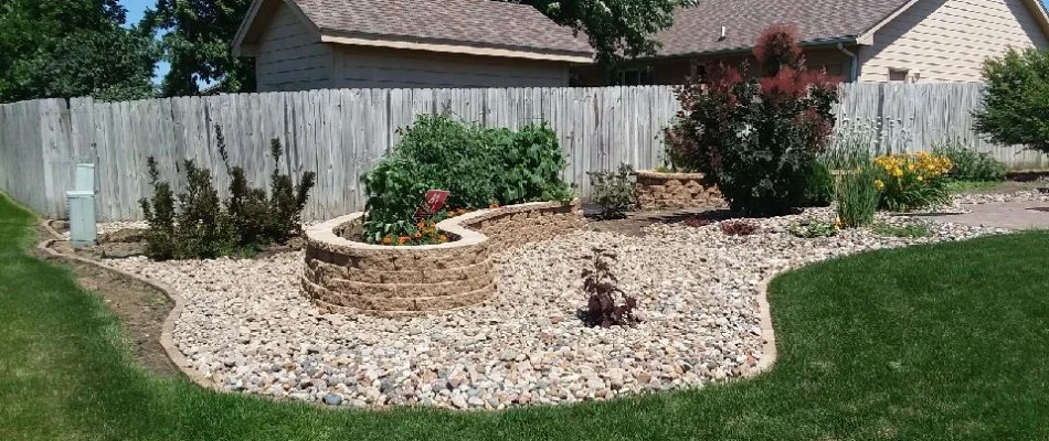 Landscape in Slater, IA, with rocks, planter beds, shrubs, and flowers.