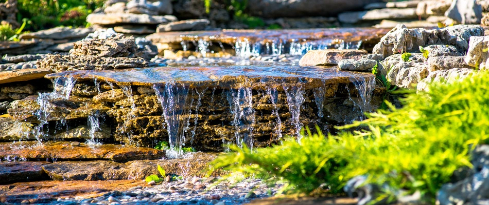 Close up on a small waterfall within a custom built stream on a property in Clive, IA.